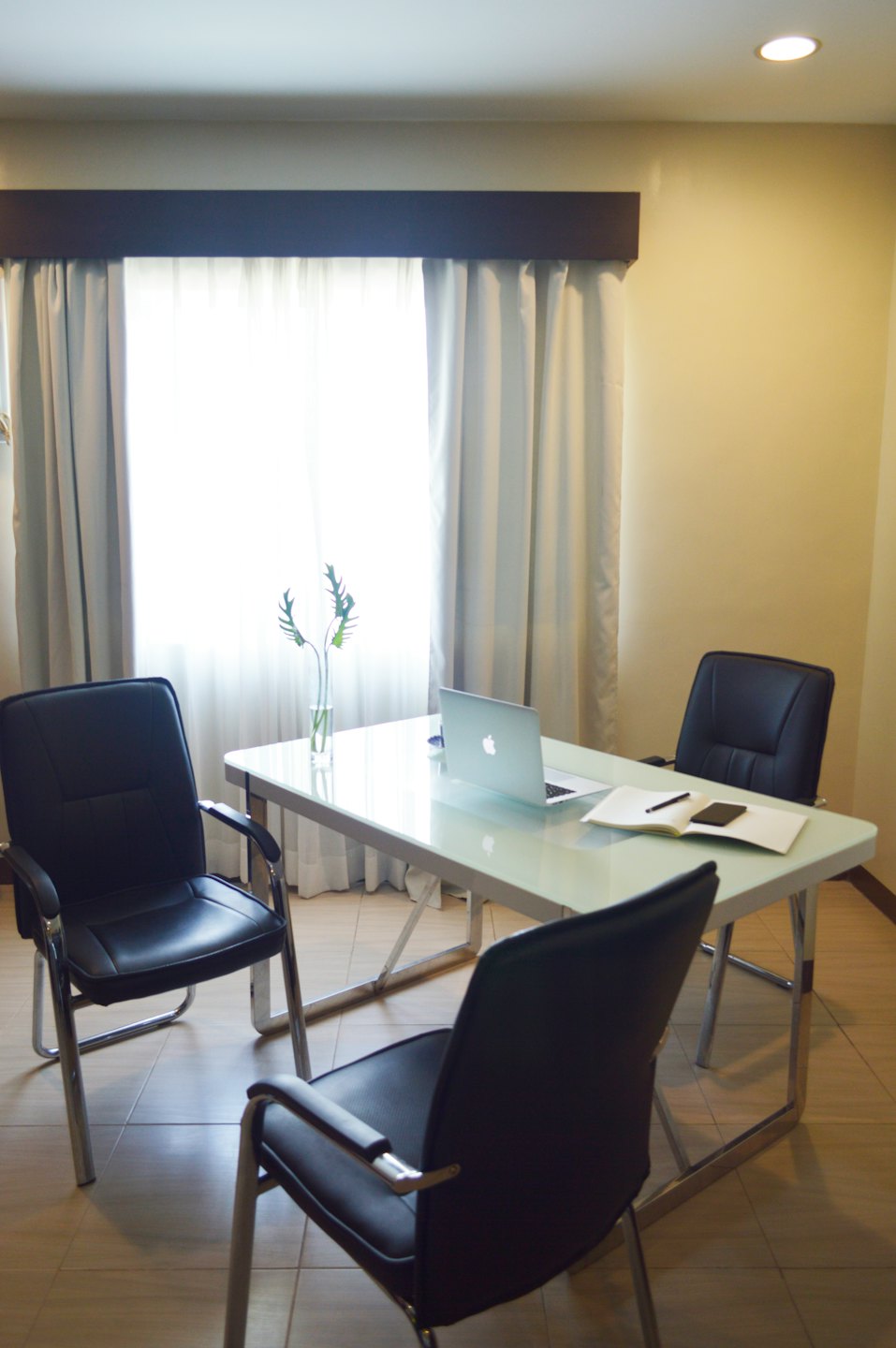 A tidy office meeting room with a laptop and chairs.